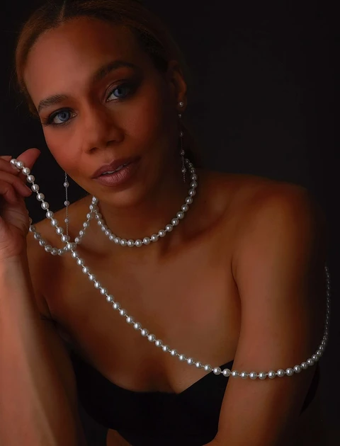 Daisi Jo in a black top with layered pearl jewelry