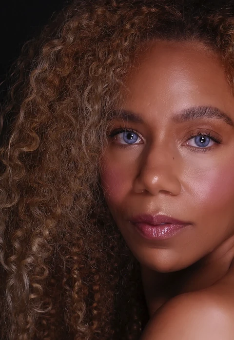 Daisi Jo — beauty close-up with curly hair against a dark background