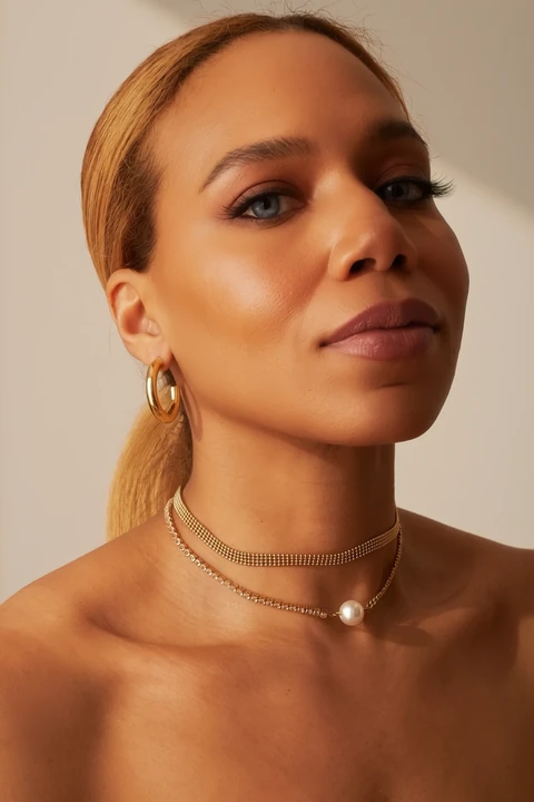 Daisi Jo — portrait with layered necklaces and earrings