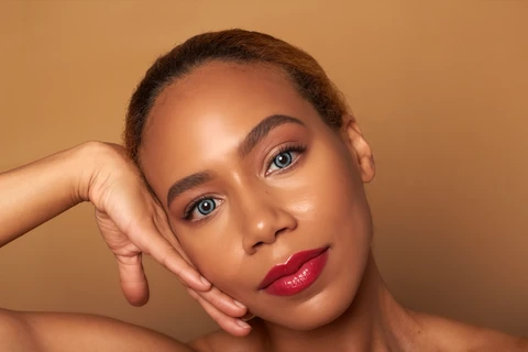 Daisi Jo — beauty portrait with red lipstick and a hand resting beside her face