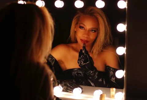 Daisi Jo — glamour portrait applying red lipstick in a lighted mirror