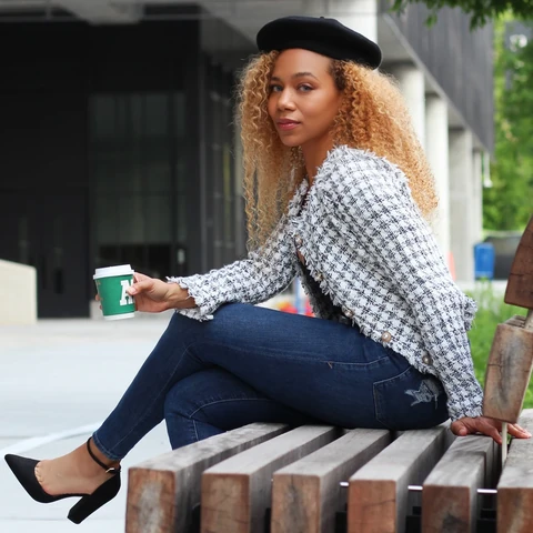 Daisi Jo — seated outdoors with a coffee, wearing a tweed jacket, jeans and a black beret