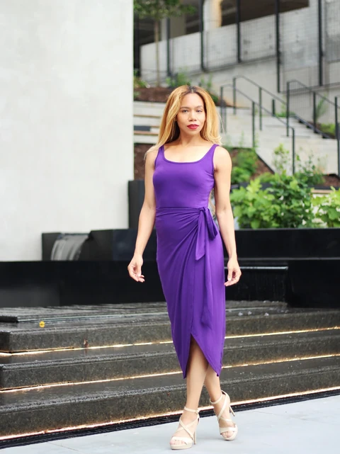 Daisi Jo modeling a purple wrap dress and cream heels outdoors