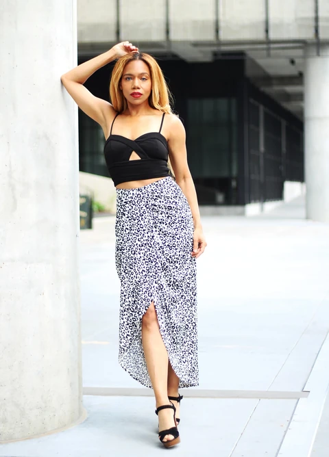 Daisi Jo modeling a black crop top and animal-print skirt with one arm raised