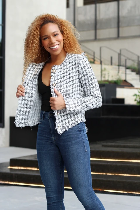 Daisi Jo smiling in a tweed jacket, black top and blue jeans