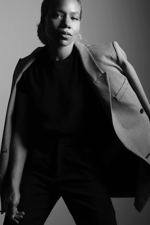 Black-and-white fashion portrait of Daisi Jo in a checked blazer and black top