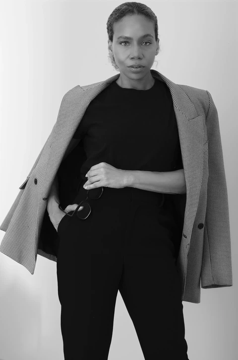 Black-and-white portrait of Daisi Jo with a checked blazer draped over her shoulders