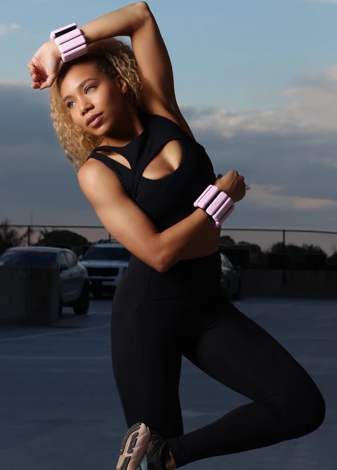 Daisi Jo posing in black activewear with pink wrist weights